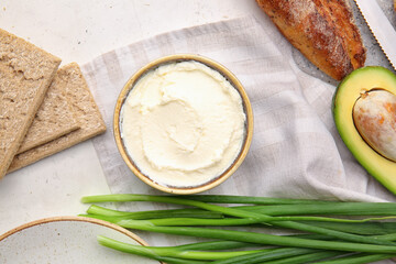 Bowl with tasty cream cheese on light background