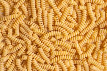 Raw durum wheat pasta, fusilli background. Top view