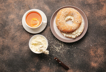 Bagel with tasty cream cheese and cup of tea on grunge background