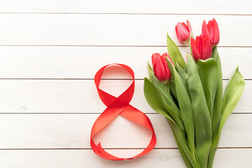 Red tulips and red number eight for international womens day over white wooden table background