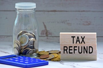 Glass jars with blurred multicurrency coins, calculator and text on white torn paper - Tax refund