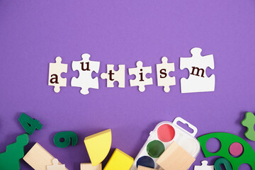 inscription autism on plasmas, purple background, copy space, developing toys and paints for training and diagnosis