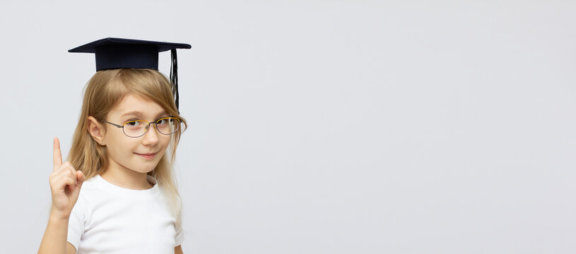 childhood, school, education, learning and people concept - happy girl with glasses in bachelor hat or mortarboard over white background