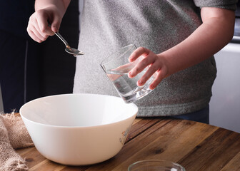 person holding spoon and glass of water preparing dough