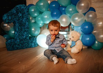 baby child with balloons having his birthday against blue balloons