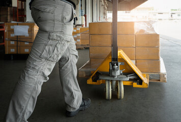 Worker working with hand pallet jack unloading cargo boxes at storage warehouse. shipment boxes.	 