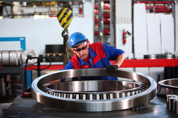 The worker moves a large diameter bearing. Bearing plant. The displacement of the bearings of large...