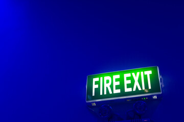 Green emergency fire exit sign on blue wall.