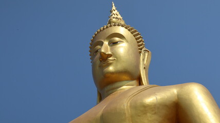 Fototapeta premium Buddha statue soars isolated into blue sky