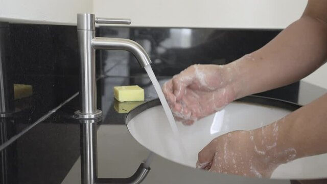 Slow motion man lathering hands with soap, Close up  Man cleaning hand and have water flowing at basin in bathroom,Hand washing with soap or using hand sanitizer gel for prevent coronavirus infection