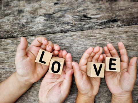 Inspirational Concept - LOVE text on wooden blocks with palms background. Stock photo.