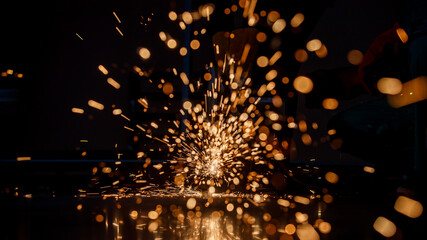 spark in a dark background from a hot red metal cut by a steel cutting machine in a factory. Nice...