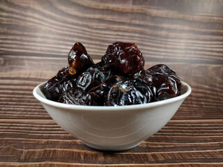 Selective focus.Dried sweet dates on bowl on wooden table background. Healthy food concept.