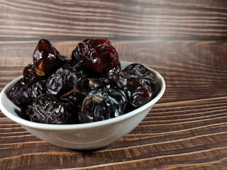 Selective focus.Dried sweet dates on bowl on wooden table background. Healthy food concept.