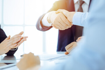 Businesspeople or lawyers shaking hands finishing up meeting or negotiation in sunny office. Business handshake and partnership