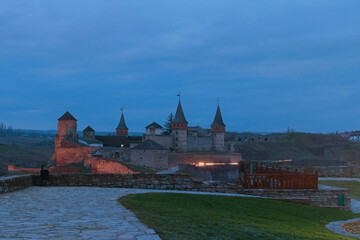 Naklejka na ściany i meble Wide angle landscape view of medieval Kamianets-Podilskyi Castle against morning blue sky. Famous touristic place and travel destination, Ukraine.
