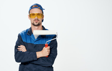 A man repairs yellow glasses and a roller to paint the walls