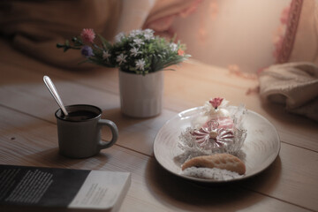 cup of coffee with book and some sweets in a wooden background