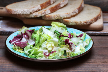 Healthy salad and bread on a wooden table.