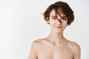 Beauty. Young caucasian woman with naked body and no makeup facial skin, hydrated and clean face after cleansing gels and face cream, standing over white background
