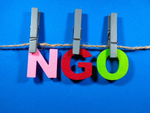 Selective focus.Word NGO (Non Government Organization) with clothespins on blue background.Business concept.