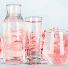 pink flowers distorted through water in glasses and bottle on blue background. Home decor, eco friendly, relax, gardening concept. copy space. square