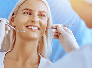 Smiling blonde woman examined by dentist at dental clinic. Healthy teeth in medicine concept