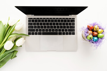 Women workspace mockup laptop computer, white tulip flowers and easter eggs in a bucket