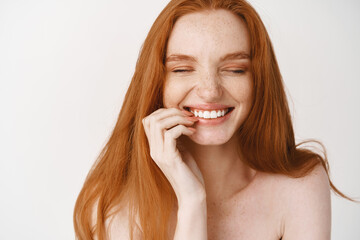 Close-up of happy redhead woman with pale no makeup skin and perfect smile, laughing and looking...