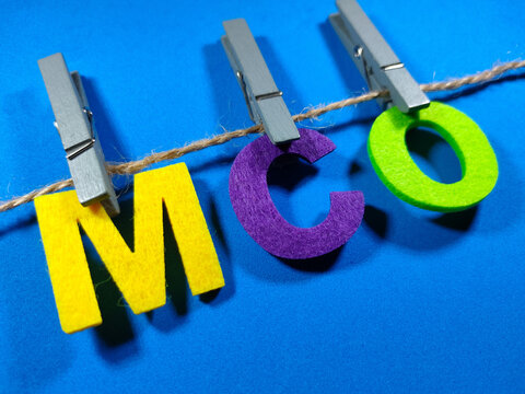 Selective focus.Word MCO (Movement Control Order) with clothespins on blue background.Pandemic concept.