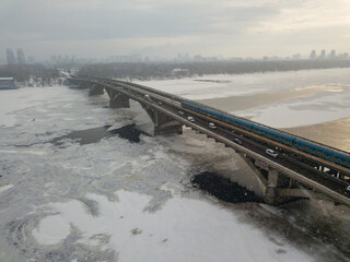 The Kiev metro train travels across the bridge through the Dnieper river. Aerial drone view. Winter...