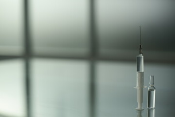Medicine vial and syringe on glass table