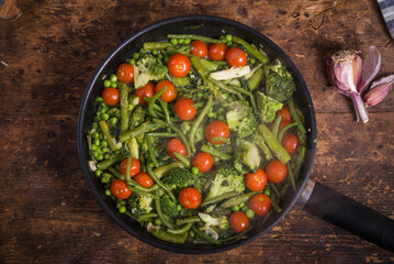 The preparation of useful vegetable dishes in a pan - broccoli, asparagus, peas and beans with tomatoes cherry in a frying pan, vegetables for cooking pasta Primavera