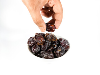 Selective focus.Hand holding dried sweet dates on bowl isolated on white background. Healthy food concept.