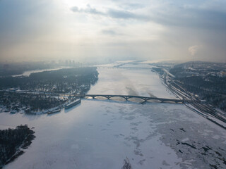 Fototapeta na wymiar The frozen Dnieper river in Kiev. Aerial drone view. Winter frosty morning. The sun breaks through the clouds.