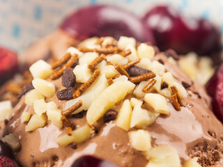 Chocolate ice cream with sprinkles, nuts and fresh cherries, closeup.