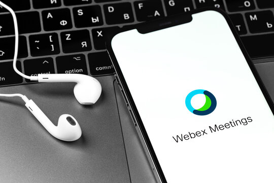 Webex Meetings app on display smartphone iPhone, EarPods headphones, laptop. Webex Meetings is one of popular application offering cloud meeting or video conference. Moscow, Russia - December 3, 2020