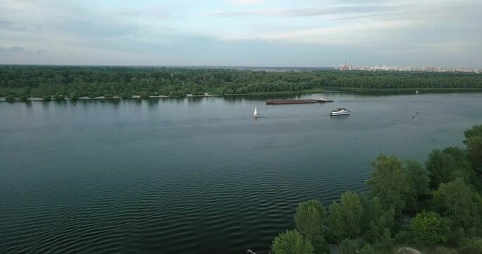 Drone flight over the river overlooking the tug barge and sailboat in the evening, sunset. Ukraine