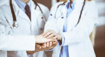Group of modern doctors joining hands as a circle and ready to help patients. Teamwork in medicine during Coronavirus pandemic. Covid 2019