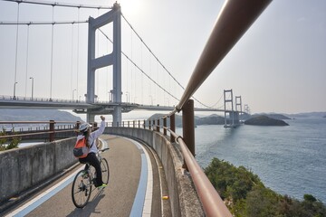 日本の来島海峡大橋にある自転車道でサイクリングを楽しむ人　ナショナルサイクルルート「しまなみ海道サイクリングロード」