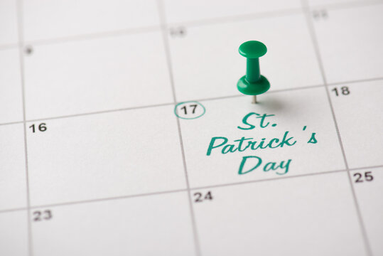 Happy Saint patrick's Day concept. Close up cropped view photo image of push pin attached to calendar with date of the holiday