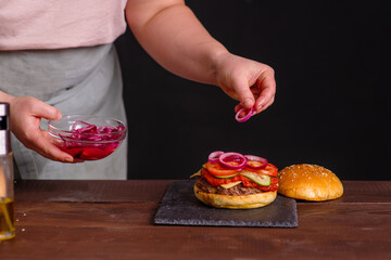Obraz na płótnie Canvas Close-up on the preparation of a magnificent burger. Gastronomy, recipes, menus, fast food. Juicy hamburger