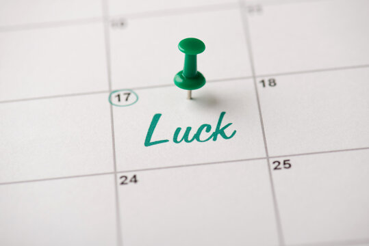 Happy St. Patrick's day concept. Cropped close up view photo of thumbtack attached to white paper calendar with word luck