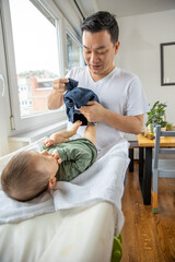 Father changing diapers to his newborn son