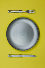 gray plate and cutlery on yellow background