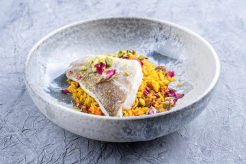 Modern style traditional sauteed skrei cod fish filet with skin in a bed of Persian jeweled saffron...