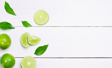 Set of fresh whole and cut lime slices on white wooden table background. top view.