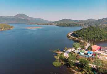 Fototapeta na wymiar Aerial View over blue lake and green mountain at sunrise. Road to mountain along Lake Thailand.