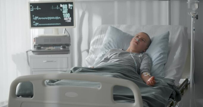 Unhappy sick kid with cancer lying in hospital bed
