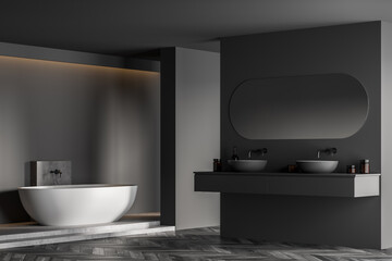 Bathtub and sinks with mirror in dark bathroom with parquet floor
